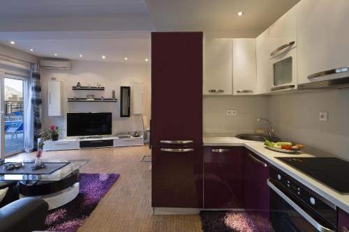 a kitchen with white cabinets and a living room at Montelux Apartments in Budva