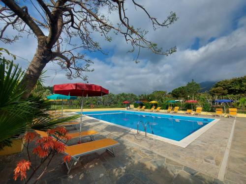 una piscina con bancos y sombrillas junto a un complejo en Camping Bella Vista en Ceriale
