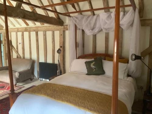 a bedroom with a canopy bed and a chair at The Granary at Duchess Farm in Sawbridgeworth