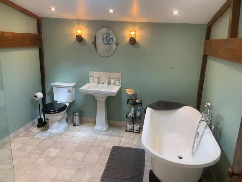 a bathroom with a tub and a toilet and a sink at The Granary at Duchess Farm in Sawbridgeworth