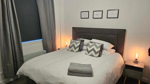 a bedroom with a bed with pillows and two lamps at Contemporary Highland Cottage in Invergordon