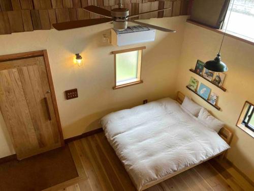 a small bedroom with a white bed and a window at 自然素材でリノベした木の香り漂う貸切宿｜藤野民宿（Fujino Guest House） in Fujino