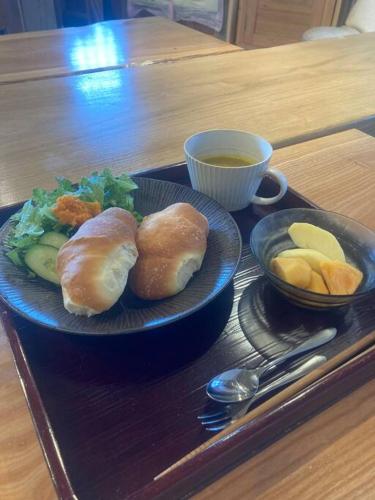 a plate of food with bread and fruit on a table at 自然素材でリノベした木の香り漂う貸切宿｜藤野民宿（Fujino Guest House） in Fujino