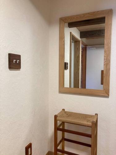 a mirror on a wall with a wooden stool at 自然素材でリノベした木の香り漂う貸切宿｜藤野民宿（Fujino Guest House） in Fujino