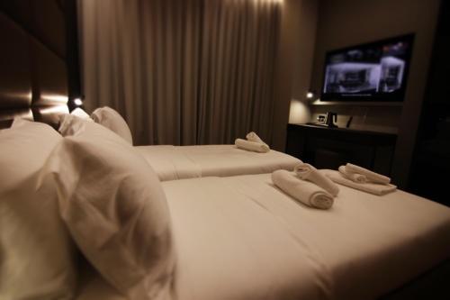 two beds in a hotel room with towels on them at Boutique Hotel Adelar in Tirana