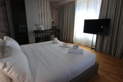 a bedroom with a white bed with towels on it at Boutique Hotel Adelar in Tirana