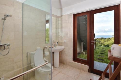a bathroom with a toilet and a sink and a window at Moritz Palm Villa in Uluwatu