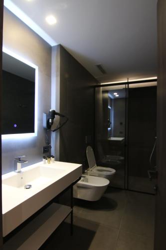 uma casa de banho com 2 lavatórios, um WC e um espelho. em Boutique Hotel Adelar em Tirana