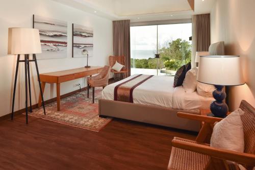 a bedroom with a bed and a desk and a window at Moritz Palm Villa in Uluwatu