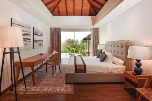 a bedroom with a bed and a desk and a table at Moritz Palm Villa in Uluwatu