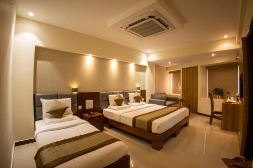 a hotel room with two beds and a couch at Metro Plaza Hotel in Mangalore