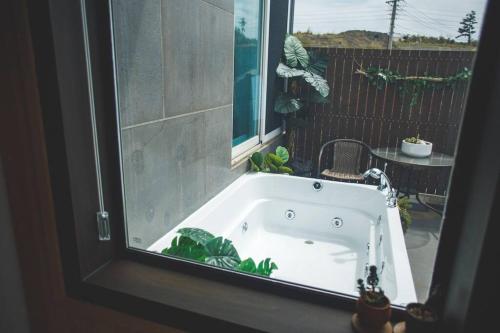 a bath tub in front of a window at Siyoung's House in Jeju