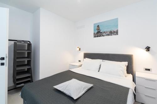 a white bedroom with a bed with a gray blanket at The Plaza Ground Floor Apartments in Prizba