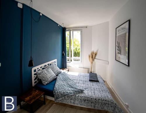 Un dormitorio con una pared de acento azul y una cama en Le Bataillon - Confort en Compiègne