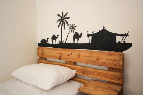 a bedroom with a bed with a wooden headboard with palm trees at Petra NefNaf Hostel in Wadi Musa