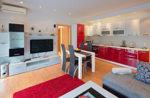 a living room with a table and a kitchen with red cabinets at Montelux Apartments in Budva