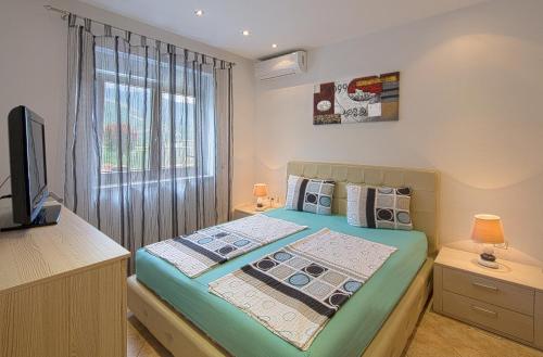 a bedroom with a bed with a television and a window at Montelux Apartments in Budva