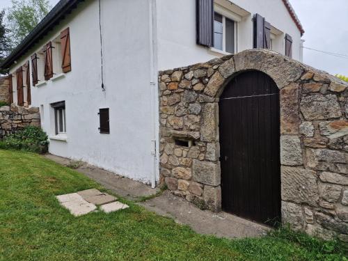 a building with a stone wall and a door at Ancienne bergerie 1000m d altitude in Chalmazel Jeansagniere