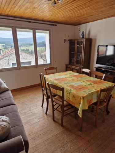 a dining room with a table with chairs and a television at Ancienne bergerie 1000m d altitude in Chalmazel Jeansagniere