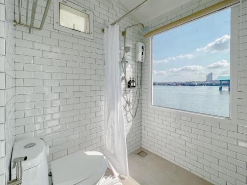 a white bathroom with a view of the water at Baan Tah On The Sea in Bang Sare