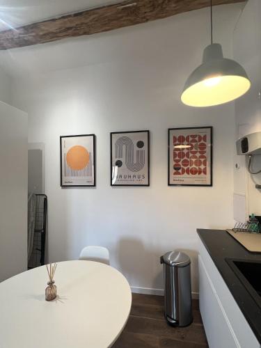 une cuisine avec une table blanche et trois photos sur le mur dans l'établissement BOHO * hypercentre * St Georges, à Toulouse