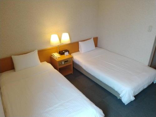 a hotel room with two beds and a telephone at Kitami Daiichi Hotel in Kitami