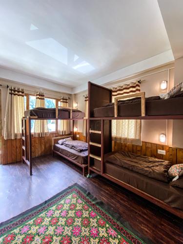 a bedroom with two bunk beds and a rug at ThePahadians Food & Stay in Jibhi