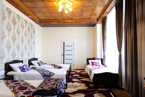 een kamer met 2 bedden met kussens en een plafond bij "Sofia" Guest House in Samarkand