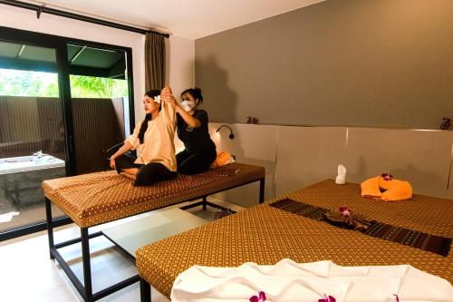 two people sitting on beds in a room at Tour De Phuket Hotel - SHA Plus in Thalang