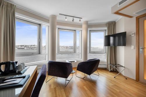 a living room with two chairs and a table with windows at Clarion Hotel Tyholmen in Arendal