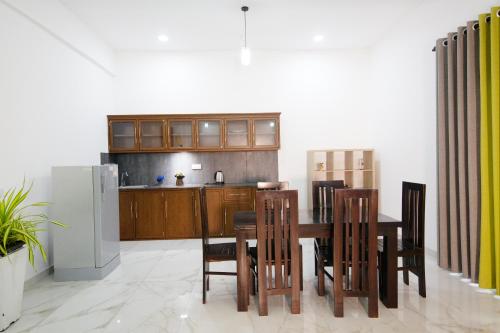 eine Küche mit einem Tisch und Stühlen sowie einem Kühlschrank in der Unterkunft Artic Holiday Homes-Apartments in Weliweriya