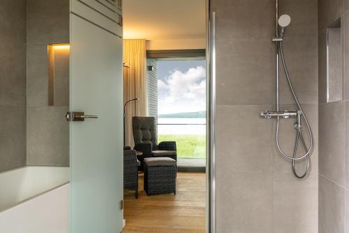 a bathroom with a shower with a chair and a window at LUV - Haus am See in Streu