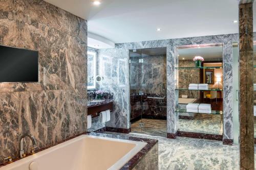 a bathroom with a tub and a television on a wall at Sheraton Oman Hotel in Muscat