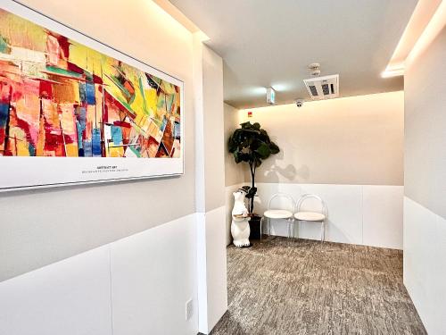 a hallway with a painting on the wall and two chairs at 东京上野超级中心 设计师房间Ybob 上野公园3分钟 车站1分钟 超级繁华 免费wifi 戴森吹风 in Tokyo