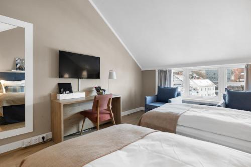 a hotel room with two beds and a desk with a mirror at Clarion Hotel Tyholmen in Arendal