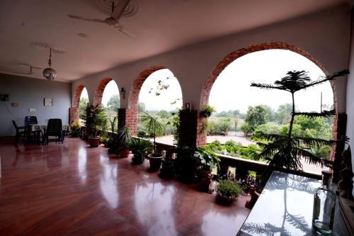 a room with arched windows and potted plants in it at lalita homestay countryside in Khajurāho