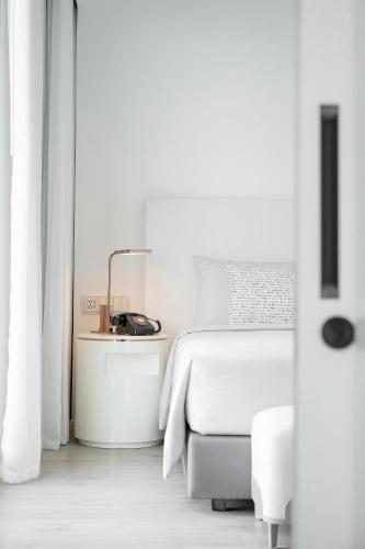 a white bedroom with a bed and a chair at INNSiDE by Meliá Bangkok Sukhumvit in Bangkok