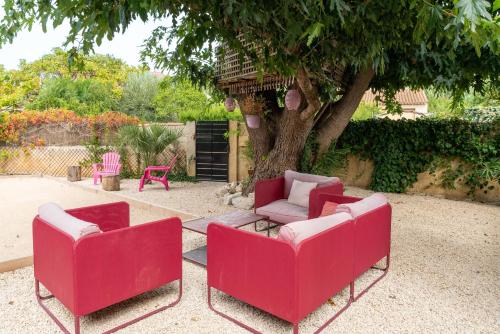two red chairs and a table in front of a tree at P'tit Bout de paradis in Cavaillon
