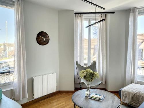a living room with a table and a clock on the wall at Le Agathe - Urbain et Bohème in Compiègne