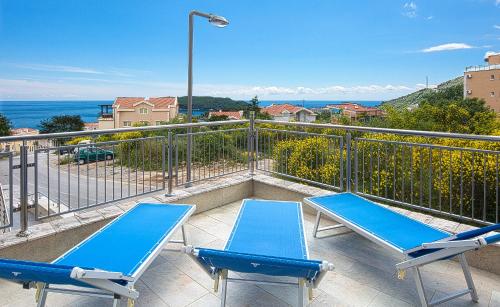 a balcony with two blue chairs and the ocean at Montelux Apartments in Budva