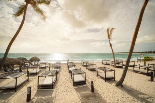 a beach area with chairs, tables and umbrellas at Punta Cana Princess Adults Only - All Inclusive in Punta Cana