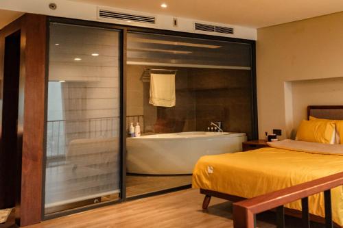 a bedroom with a tub and a bed and a bathroom at FlowerGod PentStudio Tay Ho Hanoi in Hanoi