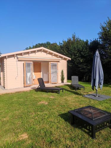 a house with a patio and an umbrella and a table at chalet de Campagne avec option SPA - petit déj 