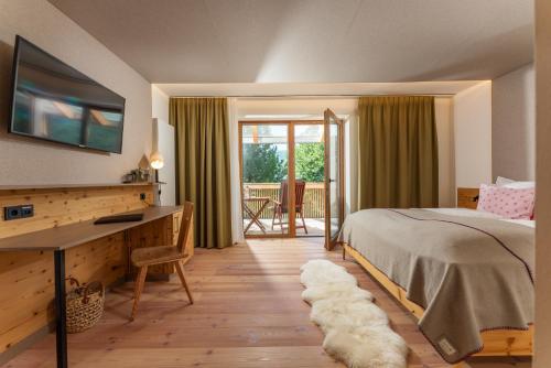 a bedroom with a bed and a desk and a balcony at Seetalblick in Sankt Wolfgang
