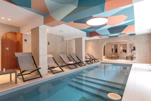 een zwembad met stoelen en een plafond met een muurschildering bij Chalet Hôtel Le Prieuré & Spa in Chamonix-Mont-Blanc