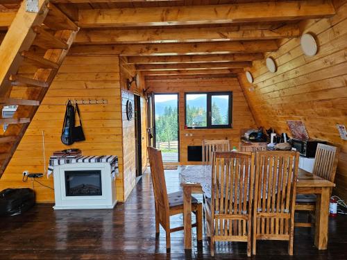 comedor con mesa y chimenea en una cabaña de madera en Cabana Corbilor The Raven's Hut, en Vatra Dornei
