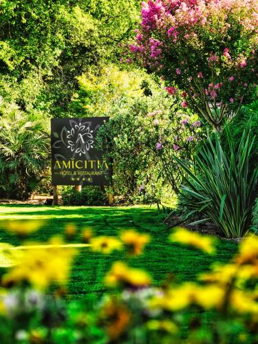 a sign in the middle of a garden with flowers at Amicitia - Hôtel & Restaurant in LʼIsle-Adam