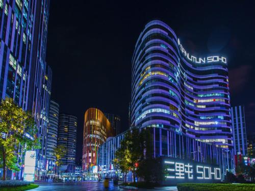 a tall building with lights on it at night at Happy Dragon City Center Alley Hotel -In the city center with big window&heater, ticket service&Free Coffee&Food recommendation,Near Tian Anmen Forbiddencity,Easy to get traditional Walking area&Shichahai in Beijing