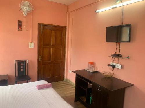 ein Schlafzimmer mit einem Bett und einem TV an der Wand in der Unterkunft Stay Inn Belle Vue House in Shillong