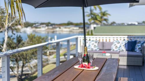 a bottle of wine on a wooden table with an umbrella at Copacabana House - Absolute Waterfront, Private Jetty in Yamba